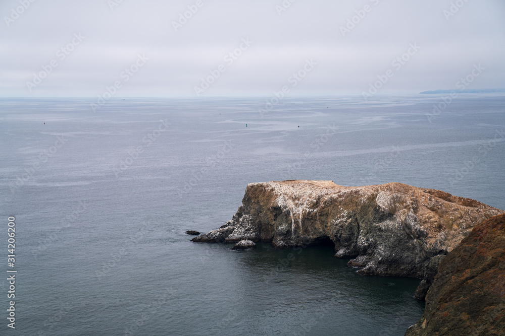 Rocks and cliff pointing out to ocean in foggy overcast