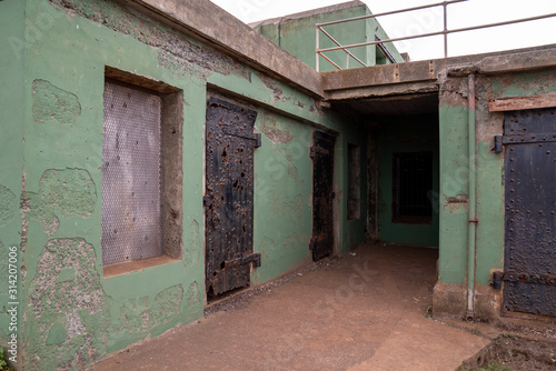Broken down prison building structure with rusted doors and crumbling paint