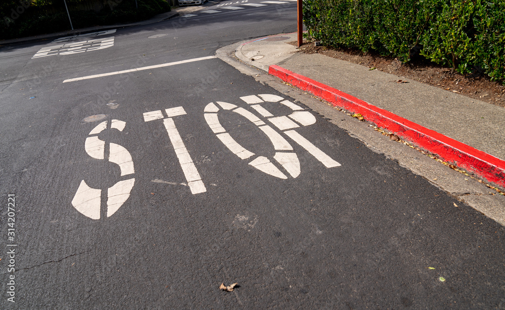 Obraz premium Stop sign painted on asphalt of red curb street at intersection