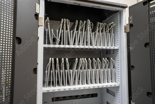 Rows of laptop computers charging in storage drawer in an enterprise of education classroom setting