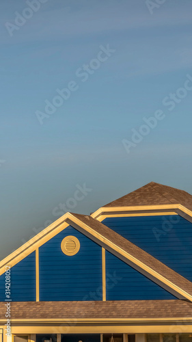 Vertical frame Close up of roof structure of home with blue gable wall and round gable window © Jason