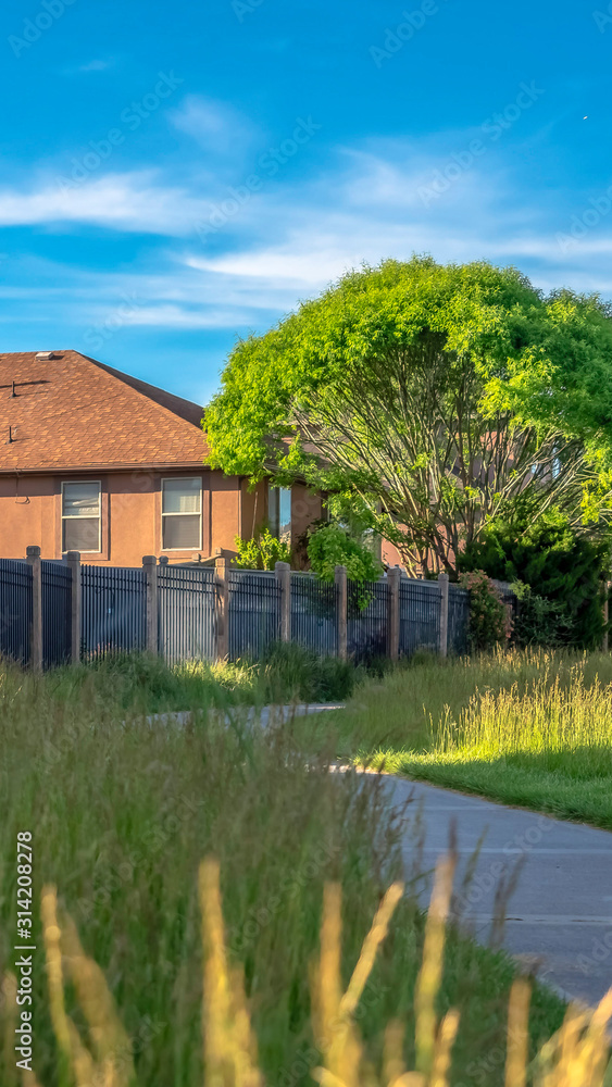 Vertical frame Views at a golf course with paved road and grasses near homes with metal fences Vertical frame Views at a golf course with paved road and grasses near homes with metal fences