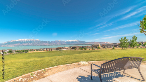 Panorama frame Park metal bench with view of lake snowy timpanogos mountains and blue sky