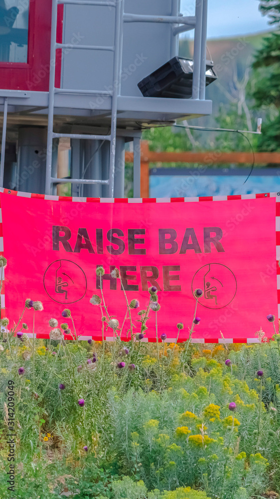 Obraz premium Vertical Raise Bar Here sign against chairlift station in Park City Utah at off season