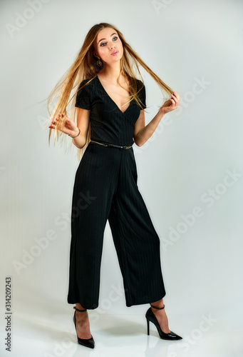 Model student manager stands in different poses in front of the camera in the studio. Full-length portrait of a pretty blonde girl with long hair and excellent make-up on a white background.