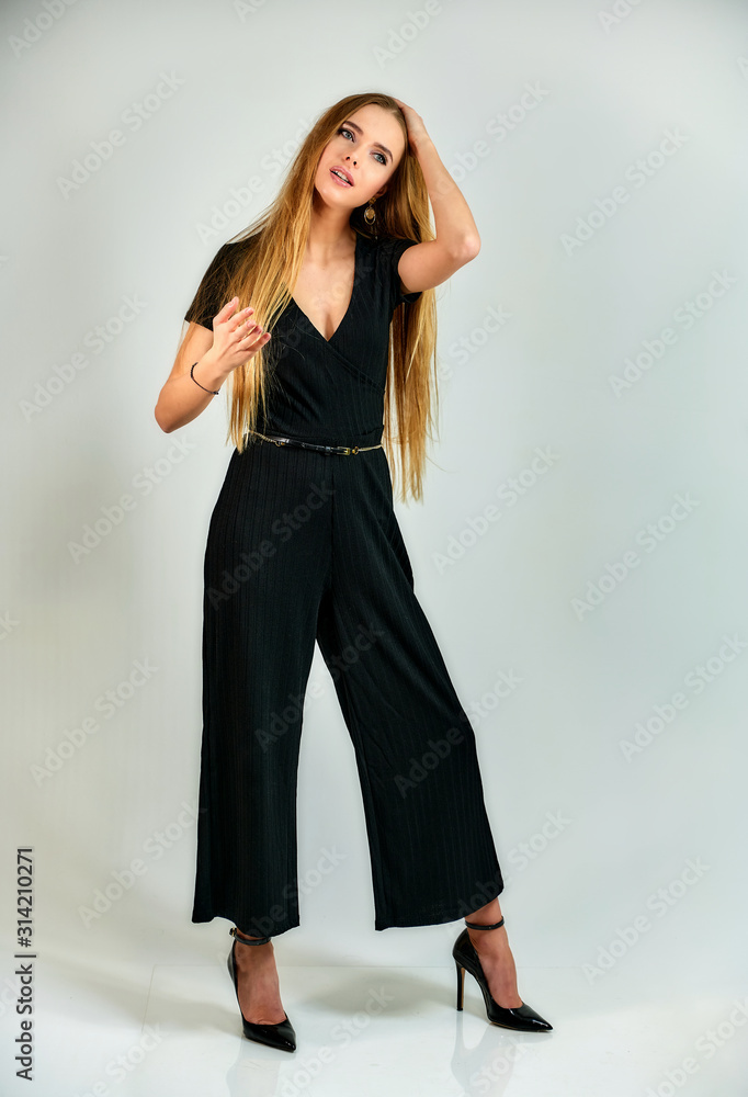 The model stands in different poses in front of the camera. The concept of fashion and style. Full-length portrait of a pretty blonde girl with long hair and excellent make-up on a white background. The model stands in different poses in front of the camera. The concept of fashion and style. Full-length portrait of a pretty blonde girl with long hair and excellent make-up on a white background.