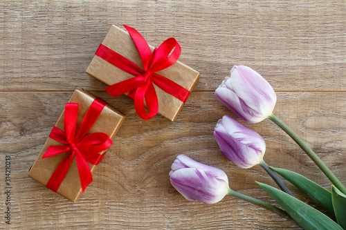 Gift boxes with tulip flowers on the wooden background.