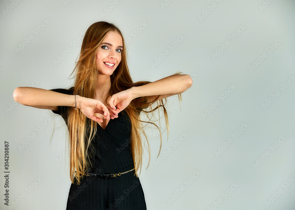 The model stands in different poses in front of the camera. The concept of fashion and style. Portrait of a pretty blonde girl with long hair and great makeup on a white background. The model stands in different poses in front of the camera. The concept of fashion and style. Portrait of a pretty blonde girl with long hair and great makeup on a white background.