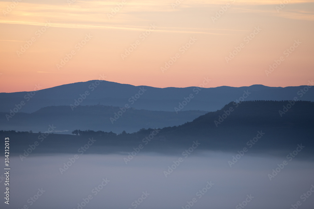 Fototapeta premium view of sunrise over the mountains mist and clouds under peaks