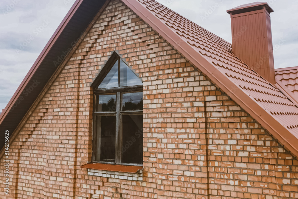 Obraz premium Beautiful pink brick brick house and orange roof. Corrugated met