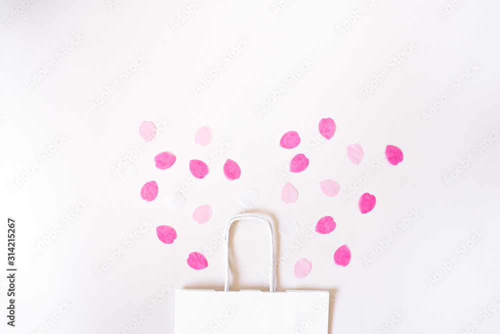 Sales and discounts. Greeting card with copy space. White paper shopping bag and paper rose petals. Sales and discounts. Greeting card with copy space. White paper shopping bag and paper rose petals.