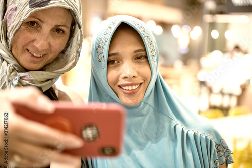 Muslim women wearing Hijab smiling taking selfies in a city mall photo