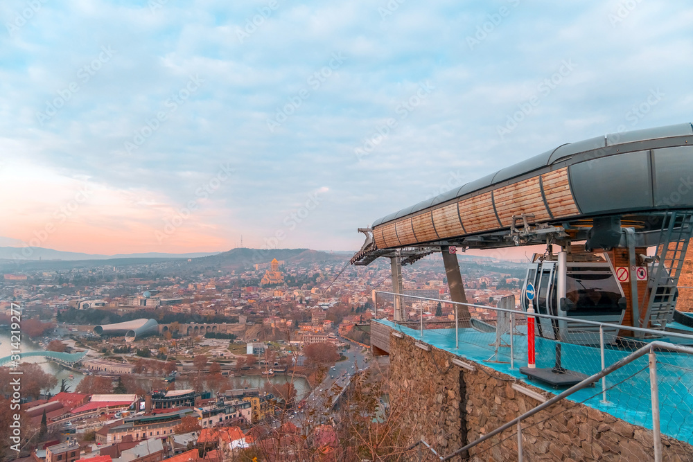 Tbilisi, Georgia, 15 December 2019 - travel card of cableway cabin on the background of cityview at the sunset