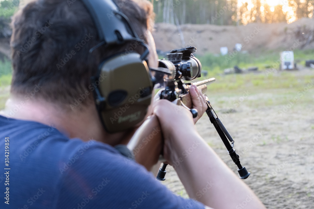 Obraz premium A man with glasses with a beard holds a sniper rifle