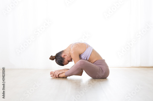 Portrait of gorgeous active sporty young woman practicing yoga in studio. Beautiful girl practice Dandayamana Bibhaktapada Paschimotthanasana, standing separate leg stretching pose. photo