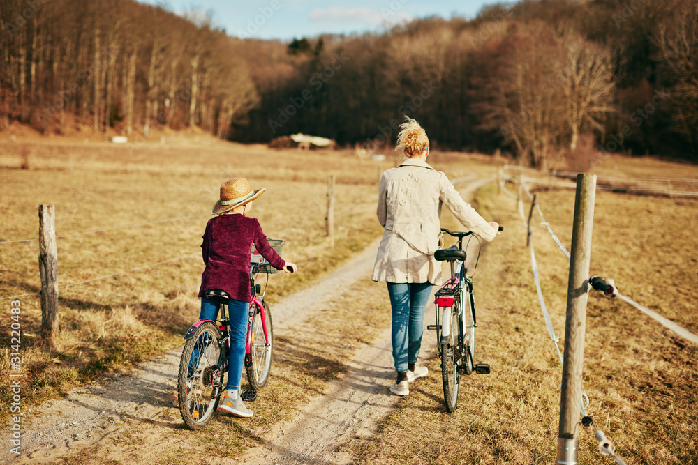 Fototapeta premium Mother and daughter with bicycles on countryside.