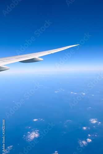 Airplane wing against the blue sky seen from a plane, travel concept.