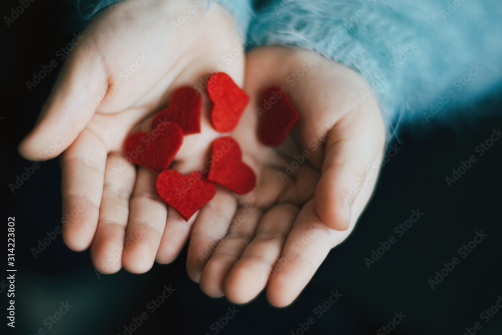 Small red hearts in childs hands. Snt Valentines day. 14 February. Heart in the arms. Love