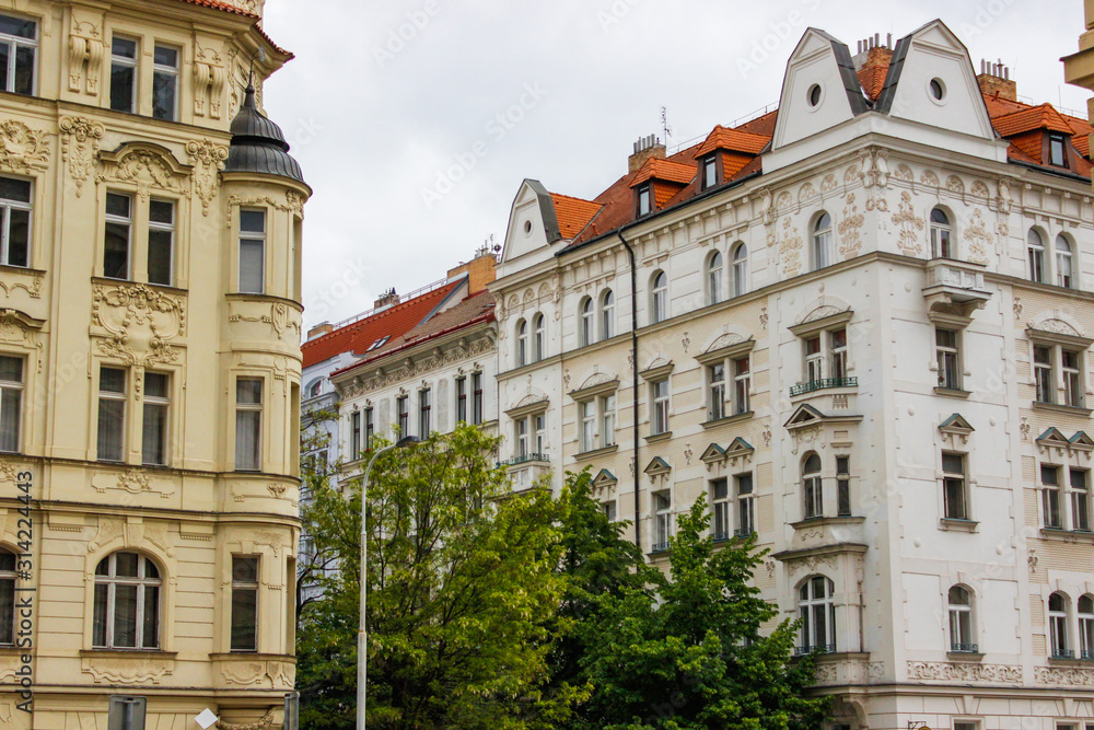 Fototapeta premium Facade of typical colorful czech houses with trees at the foreground in Prague, Czech Republic