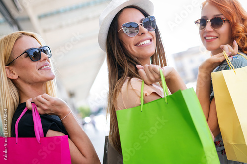 Happiness, friends, shopping and fun concept-smiling young women with shopping bags.