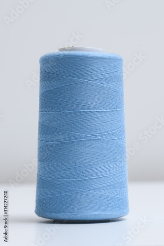 Spool of blue synthetic or cotton threads on white background. Spool of yarn using for weaving in textile manufacturing