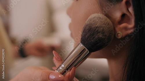 Make-up artist makes a perfect make-up for a young girl with beautiful skin. Make-up artist making professional make-up for young woman in beauty studio.