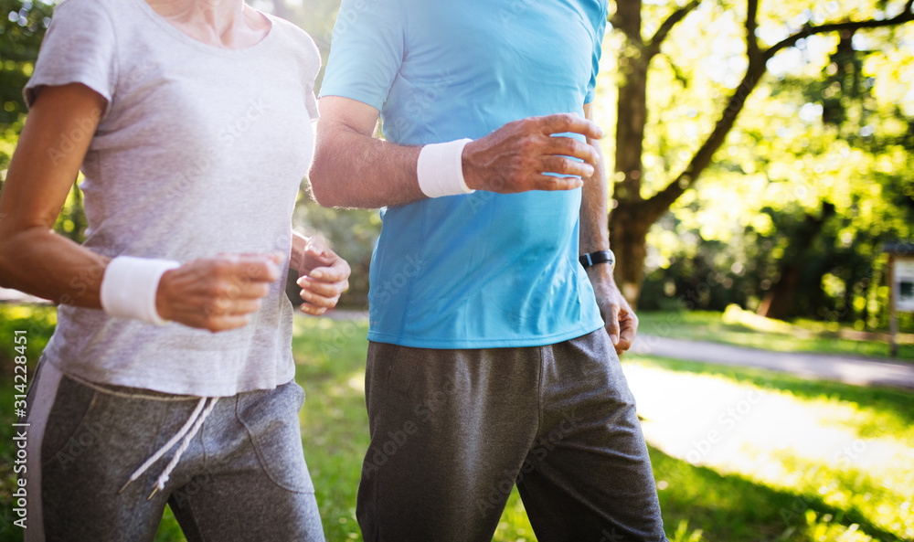 Mature or senior couple doing sport outdoors, jogging in a park Mature or senior couple doing sport outdoors, jogging in a park