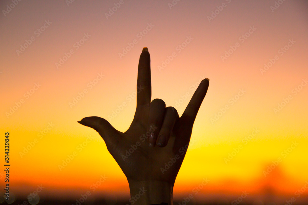 hand sign against sunset