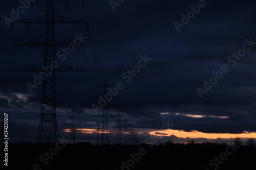 Stromleitungen bei Sonnenuntergang und bedeckter Himmel