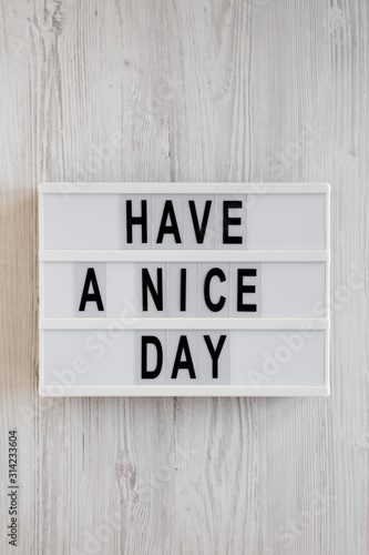 Fototapeta Naklejka Na Ścianę i Meble -  'Have a nice day' words on a lightbox on a white wooden background, top view. Overhead, from above, flat lay.