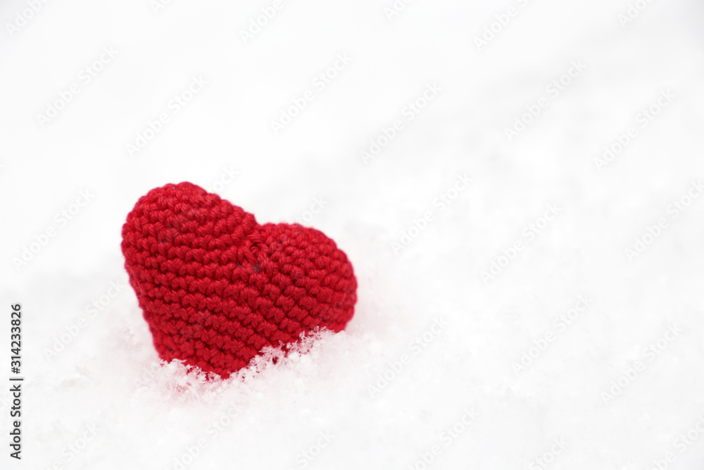 Fototapeta premium Valentine's day, red knitted heart in the snow. Background for romantic event, celebration or winter weather