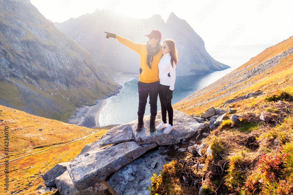 Fototapeta premium Happy couple of love are hiking on top of Mountain in Lofoten island, Norway