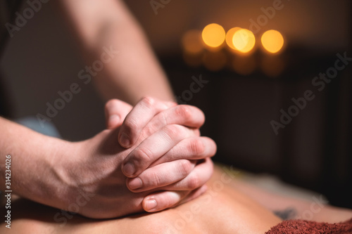 Close-up of the hands of a male masseur doing back massage to a girl at the spa. Low key high contrast shallow depth of field © yanik88