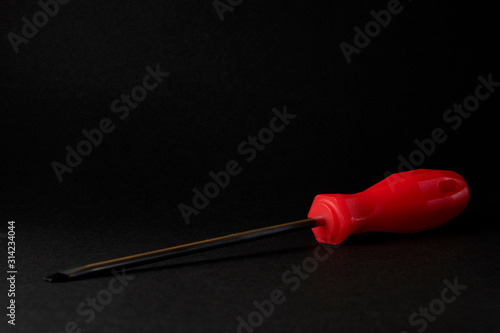 screwdriver with red handle on black background