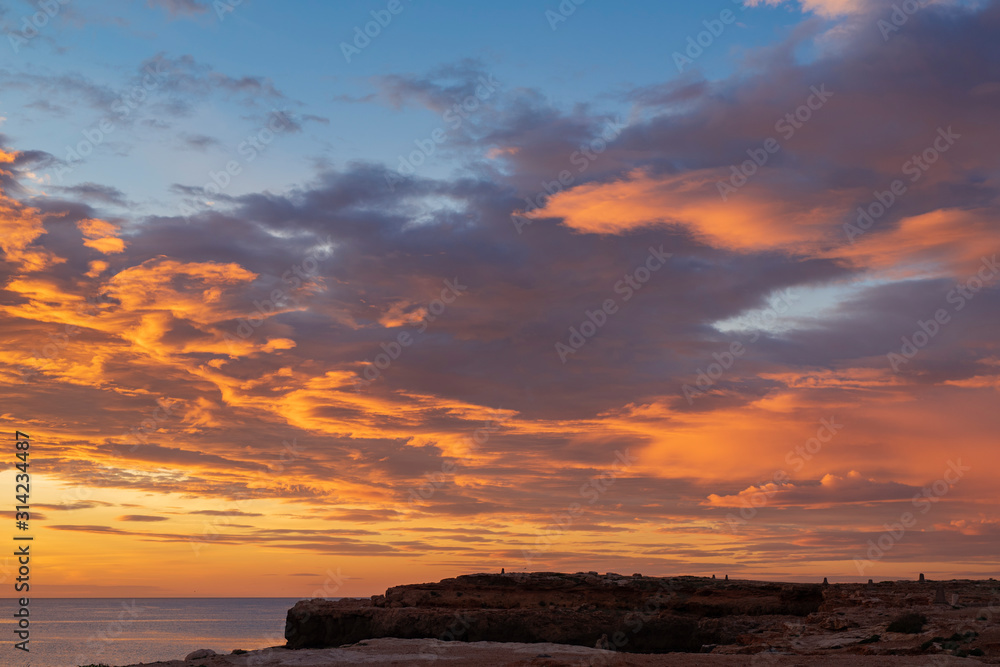 Early sunrise and epic cloudy sky at rocky seashore coast of Torrevieja, Alicante, Spain. Mediterranean sea 2019