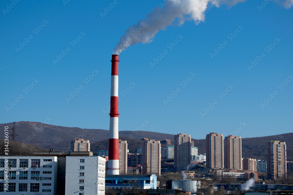 Pipe of the incineration plant releases smoke with harmful substances near the residential area. Environmental pollution, ecology.
