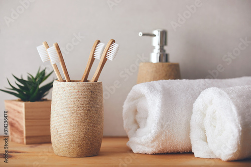 Four bamboo toothbrushes in a cup and white towels photo