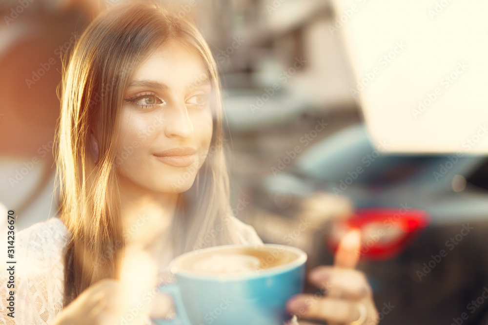 Portrait of a young woman having a cup of coffee and looking through the window Portrait of a young woman having a cup of coffee and looking through the window