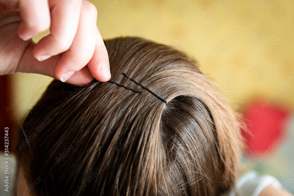 Girl pins her hair with a metal barrette
