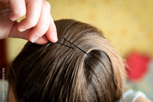 Girl pins her hair with a metal barrette
