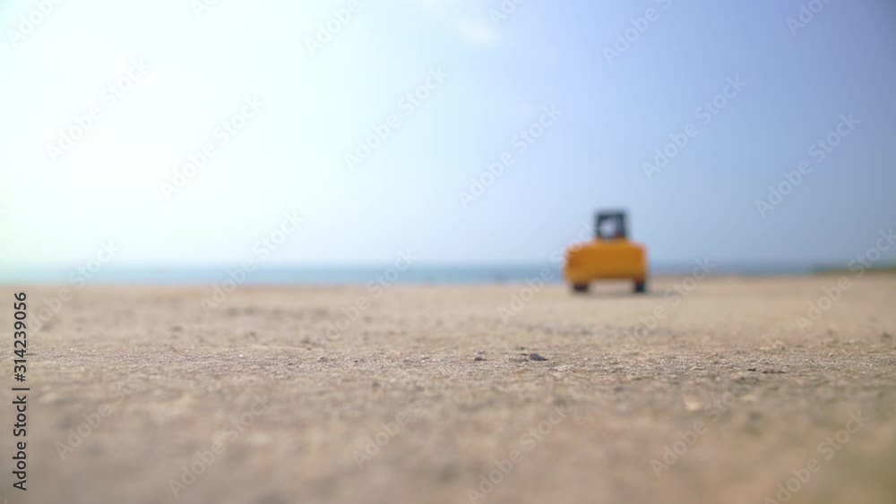 Excavator loader model approaching camera in a sunny summer day, and the man's hand taking it away at the end Excavator loader model approaching camera in a sunny summer day, and the man's hand taking it away at the end
