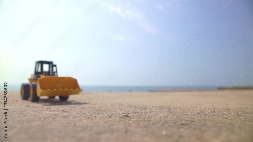 Excavator loader model approaching camera in a sunny summer day, and the man's hand taking it away at the end Excavator loader model approaching camera in a sunny summer day, and the man's hand taking it away at the end