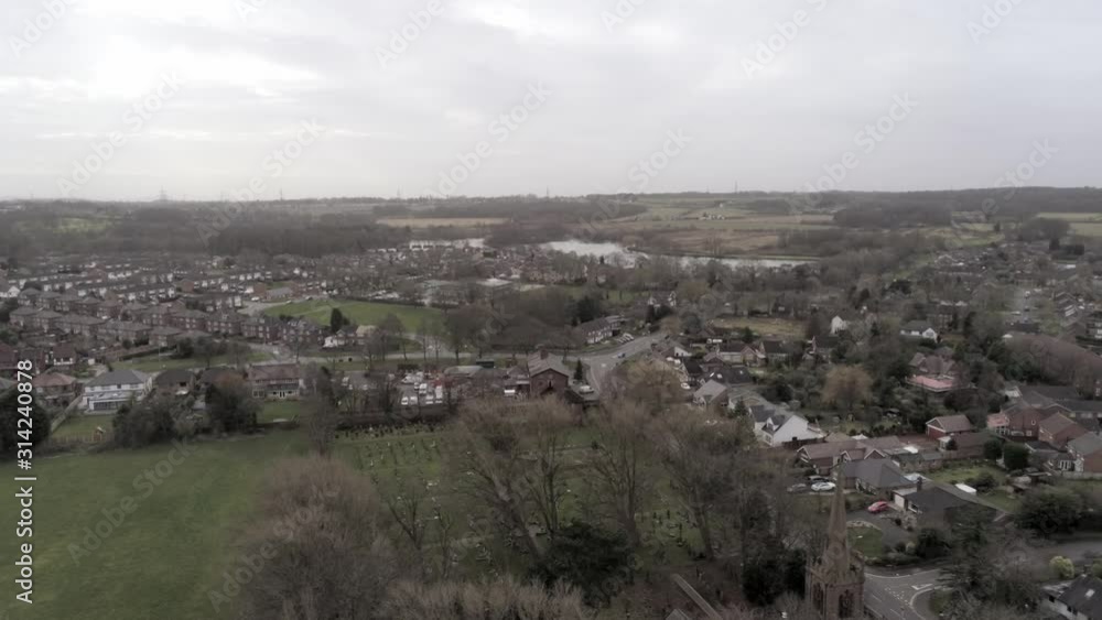 Aerial descending slow to UK Church spire in British small residential community farming village. Aerial descending slow to UK Church spire in British small residential community farming village.