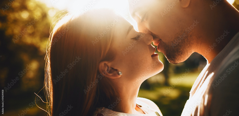 Φωτογραφία Close up portrait of a lovely young couple smiling before kissing against sunset with closed eyes outdoor in the park while dating