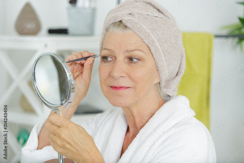 woman plucking eyebrows by the window woman plucking eyebrows by the window