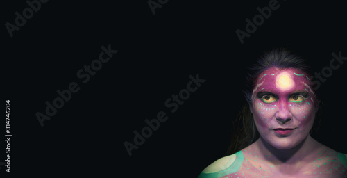 Creative makeup. Conceptual idea of bold body art painting. Abstract picture on woman face against dark background.