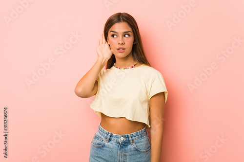 Young slim woman trying to listening a gossip.
