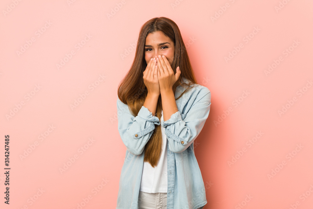 Young slim woman laughing about something, covering mouth with hands. Young slim woman laughing about something, covering mouth with hands.