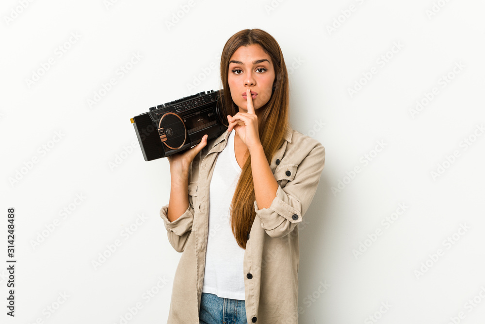 Young caucasian woman holding a guetto blaster keeping a secret or asking for silence. Young caucasian woman holding a guetto blaster keeping a secret or asking for silence.