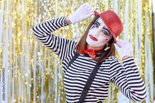 Fototapeta Naklejka Na Ścianę i Meble -  girl dressed in mime with red hat, red bow tie, striped shirt and white gloves.